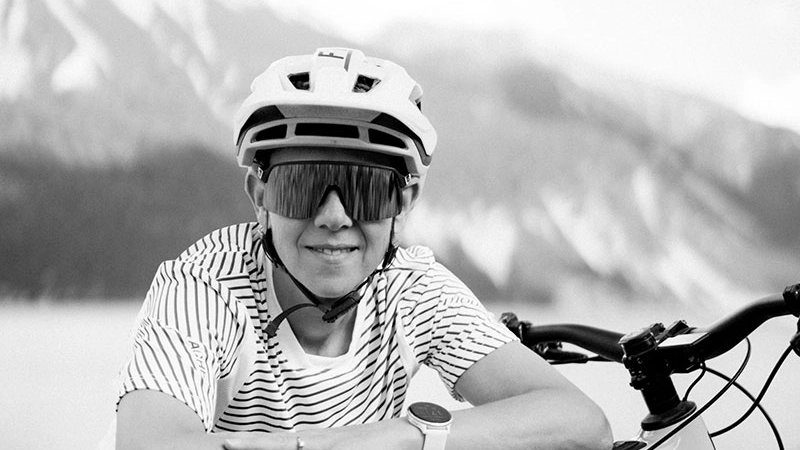 Barbara Oberdorfer lehnt lässig überm Moustache Bike, sie trägt Helm und große Sonnenbrille, Schwarz-Weiß Foto.