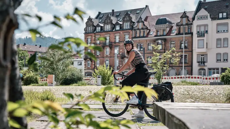 Eine Fahrradfahrerin auf dem Rad im Sommer in der Stadt Eine Fahrradfahrerin auf dem Rad im Sommer in der Stadt